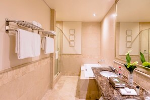 A modern bathroom with a marble countertop, a glass shower enclosure, and a large mirror. - Southern Sun Sandton (Johannesburg)
