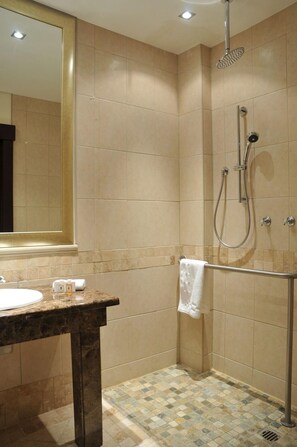 A bathroom with a shower, a sink, and a mirror. - Southern Sun Sandton (Johannesburg)