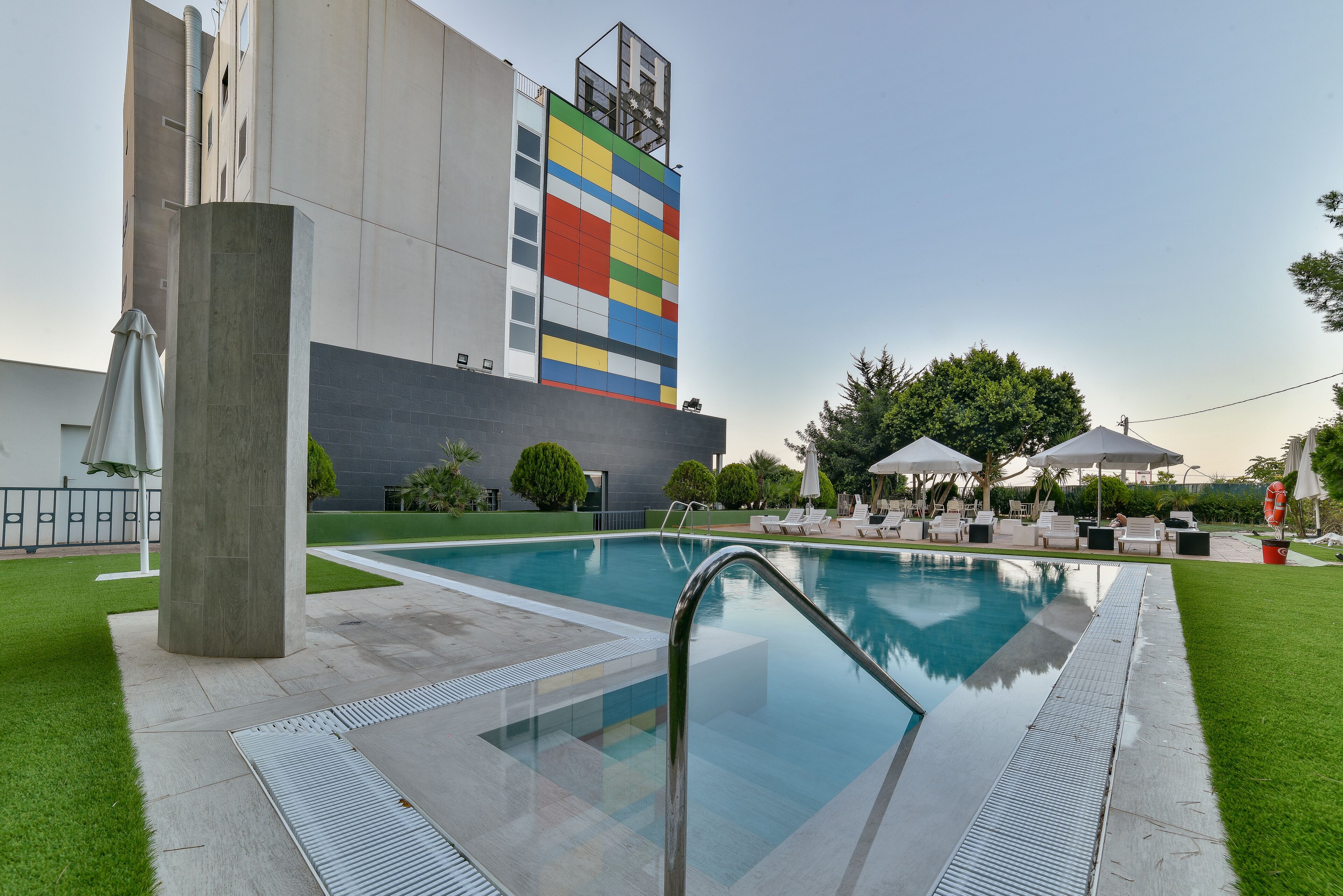 A swimming pool with a modern design, surrounded by a well-maintained lawn and lounge chairs.