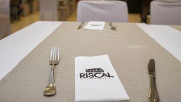 Un comedor de hotel con mesas dispuestas para una comida, un menú y un logotipo en el mantel.