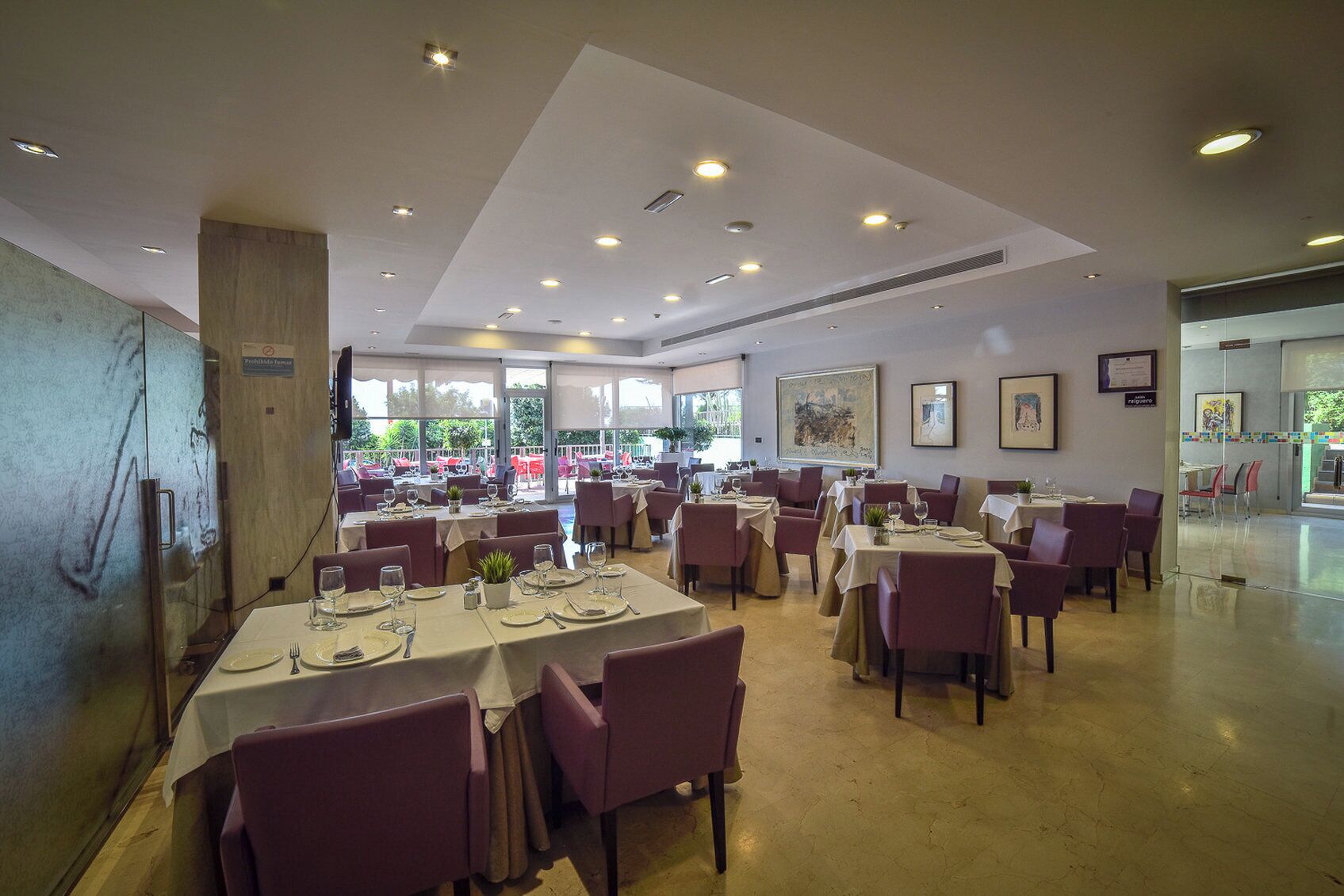 Un vaste espace dédié à la salle à manger, avec de nombreuses tables et chaises, de grandes fenêtres et des luminaires au plafond.
