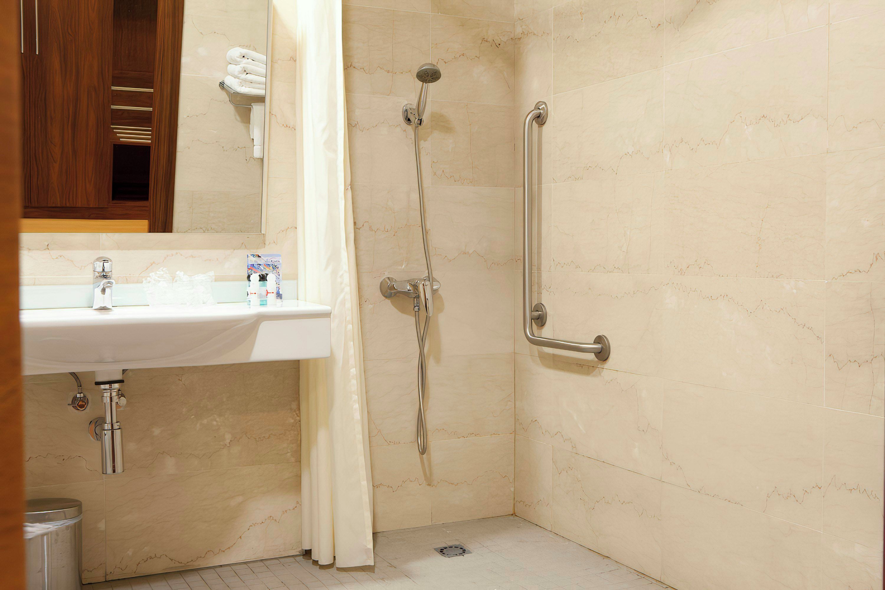A bathroom with a shower, a sink, and a handrail.