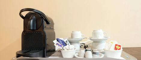 A coffee maker on a tray with various coffee cups and a teapot.