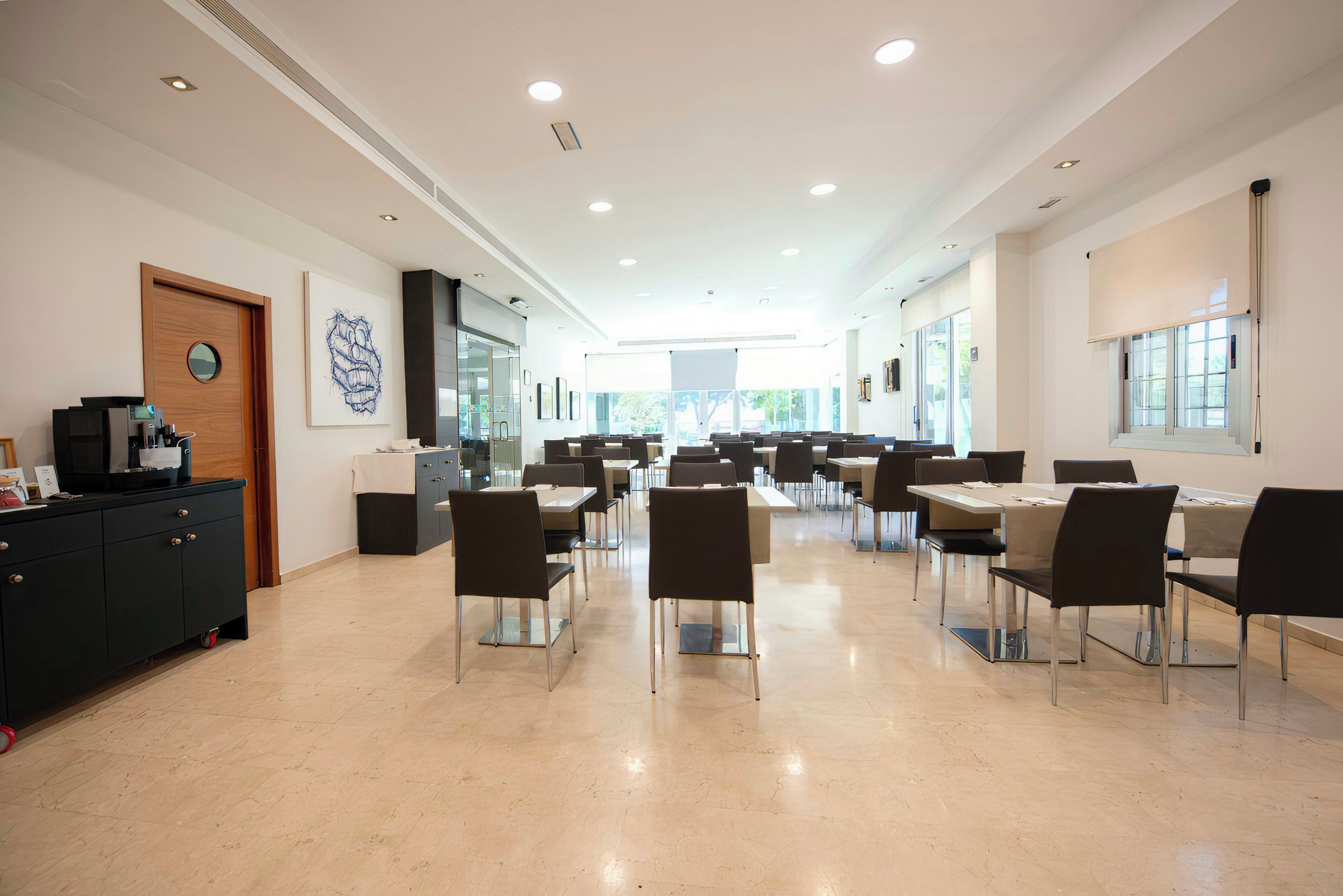 Uma sala de conferências ampla, com mesas, cadeiras, um armário de madeira e obras de arte nas paredes.