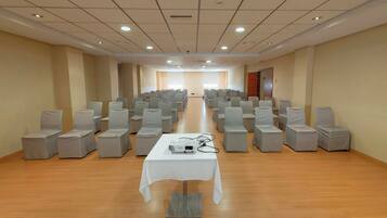 A conference room with rows of chairs, a projector on a table, and a wooden floor.