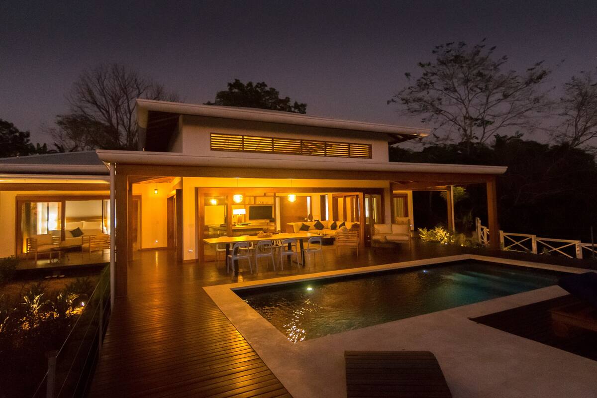 A modern house with a pool, a dining area, and a living room.