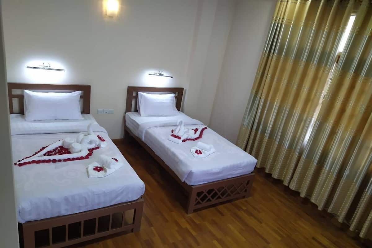 Dos camas individuales con cabeceros de madera, sábanas blancas y toallas decorativas.