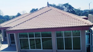 Un edificio con techo de tejas, ventanas amplias y una unidad de aire acondicionado pequeña.