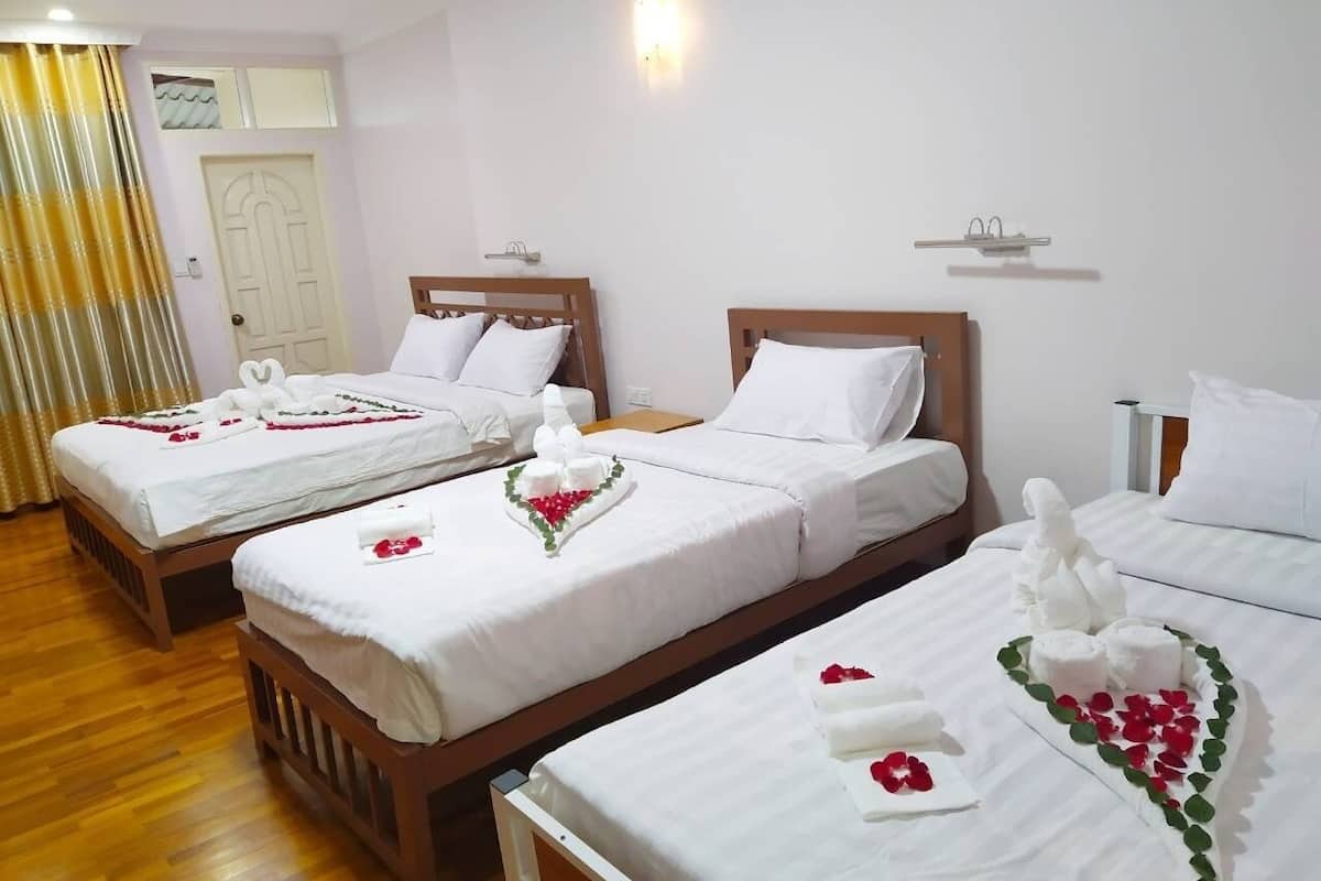 Habitación de hotel con dos camas, cada una con ropa de cama blanca y decoración floral.