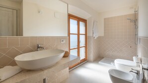 Une salle de bain moderne avec une baignoire sur pieds, un lavabo avec un grand bac, des toilettes et un espace douche.