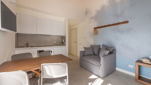 Une cuisine moderne avec des meubles blancs, une table à manger en bois et un canapé gris.