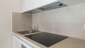 Une cuisine avec un évier en acier inoxydable, un plan de travail noir et un meuble blanc.
