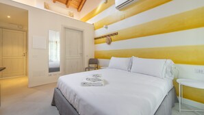Une chambre d’hôtel avec un lit, une chaise, une petite table et un miroir.