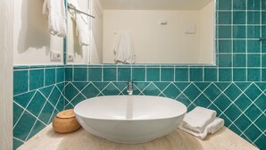 A bathroom with a white sink, teal mosaic tiles, a white towel, and a woven basket. - CA-H088-FLTI0D1 - Locanda della Meridiana - D (Pula)