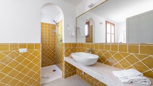 A bathroom with yellow-tiled walls, a white sink, and a shower.