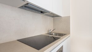 A modern kitchen with a built-in stovetop, stainless steel sink, and overhead lighting.