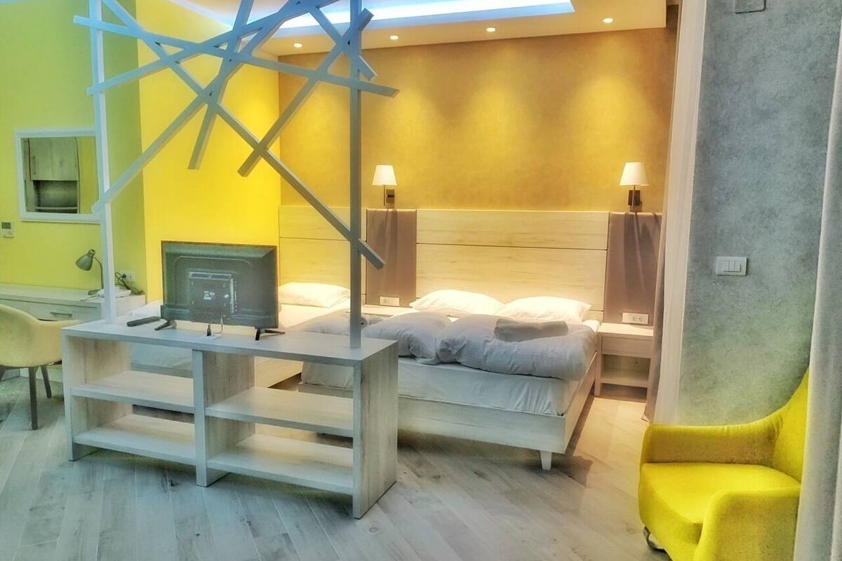 A modern hotel room with a bed, a desk, and a TV.