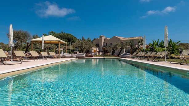 Piscina com espreguiçadeiras e um gazebo.