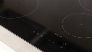 A black induction cooktop with control buttons and a power button.