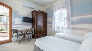 A bedroom with a bed, a TV, a wooden wardrobe, a table with chairs, and a window with curtains. - CA-H088-FLTI0LT - Locanda della Meridiana - L - Mirto (Pula)
