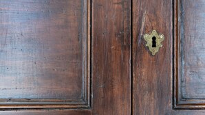 A wooden door with a brass keyhole.