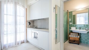 A modern kitchen with white cabinets, a stainless steel sink, and a window with sheer curtains.