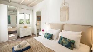 A modern bedroom with a bed, bedside tables, a mirror, and a view of the outdoors. - PRESTIGE VILLAS 'Tree Tops' - North East Coast Villa with infinity pool... (Agios Markos, Corfu)