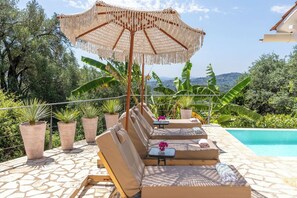 A poolside area with lounge chairs, a table, and an umbrella.