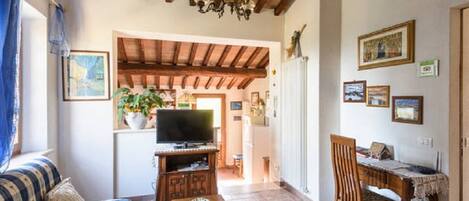 A cozy living room with a sofa, a coffee table, a TV, and a dining area with a table and chairs.
