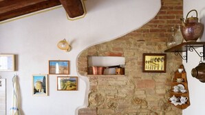 A cozy room with a stone fireplace, framed pictures, and a tea set on shelves. - Ancient farm la Martinella Depandance apartment (Siena)