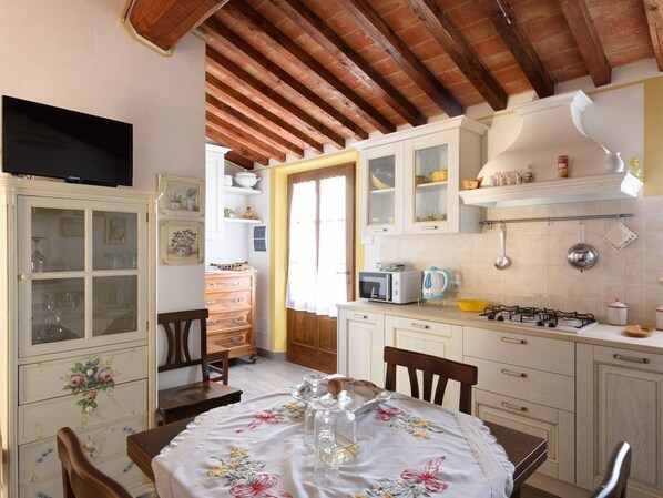 Enjoy cooking and dining in this charming kitchen with a dining table, microwave, kettle, and TV.