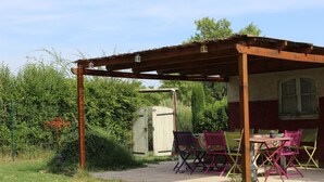 An outdoor patio with a wooden pergola, a table, and colorful chairs. - Old stone sheepfold of 129m2 and its private garden (Forcalquier)