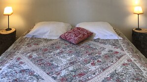 A bedroom with a bed, two bedside lamps, a hanging light fixture, and a floral painting on the wall. - Old stone sheepfold of 129m2 and its private garden (Forcalquier)