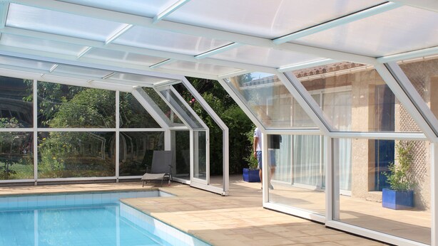 A swimming pool with a glass-enclosed patio area, clear glass walls, and a view of greenery outside. - Old stone sheepfold of 129m2 and its private garden (Forcalquier)