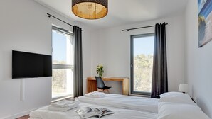 Une chambre d’hôtel moderne, dotée d’un grand lit, d’un bureau, d’une télévision et de grandes fenêtres avec des rideaux.