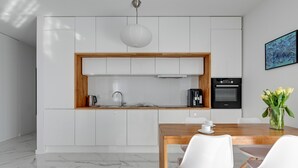 Une cuisine moderne avec des armoires blanches, un plan de travail en bois et un four encastré.