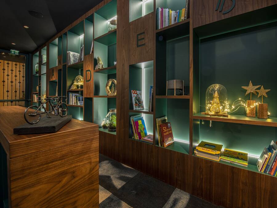 A library with wooden bookshelves, a reception desk, and various decorative items.