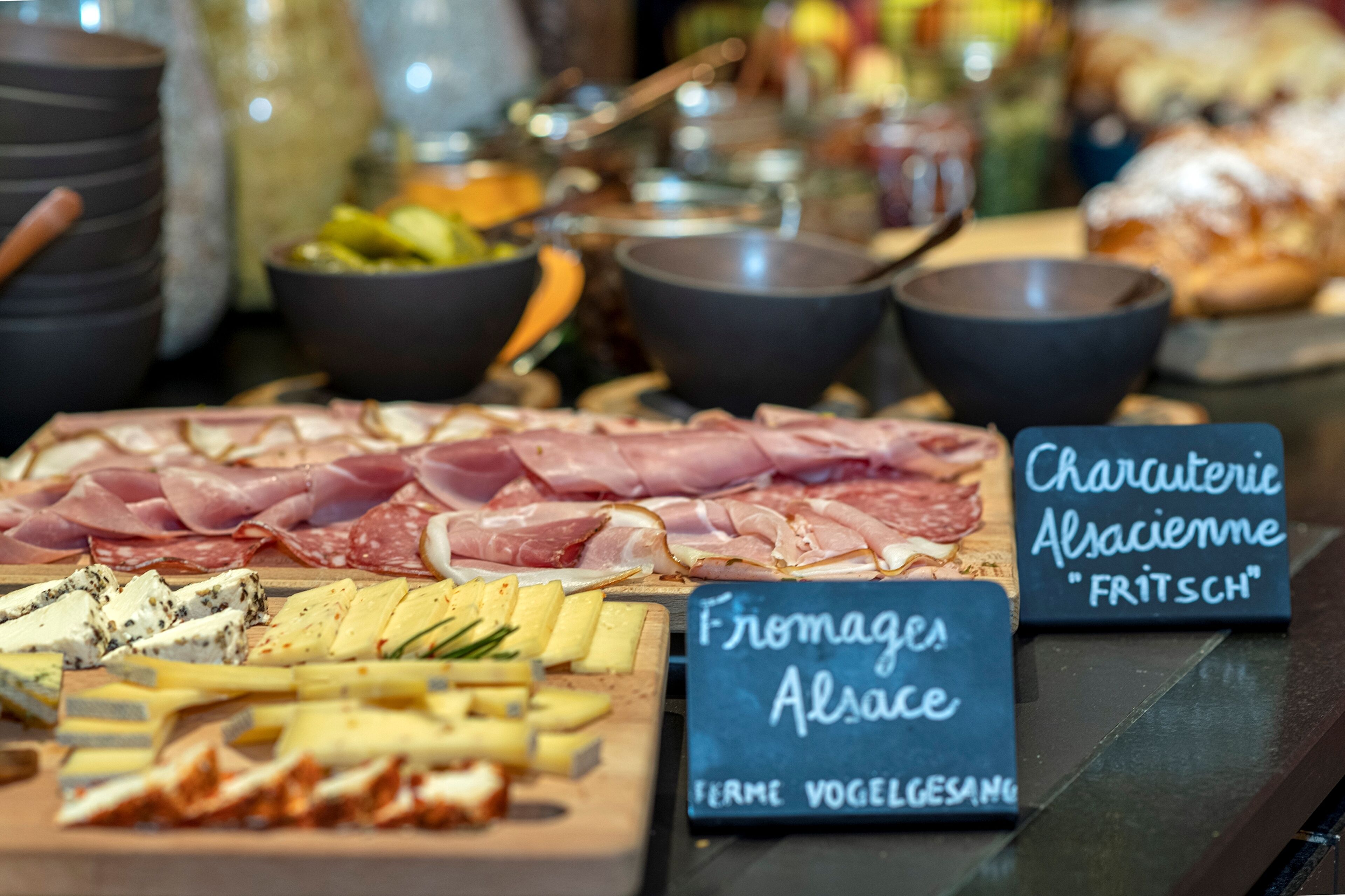 A charcuterie board with various meats and cheeses, accompanied by bowls of dips and condiments.