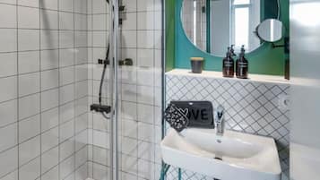 A modern bathroom with a glass-enclosed shower, a white sink, and a mirror above it.