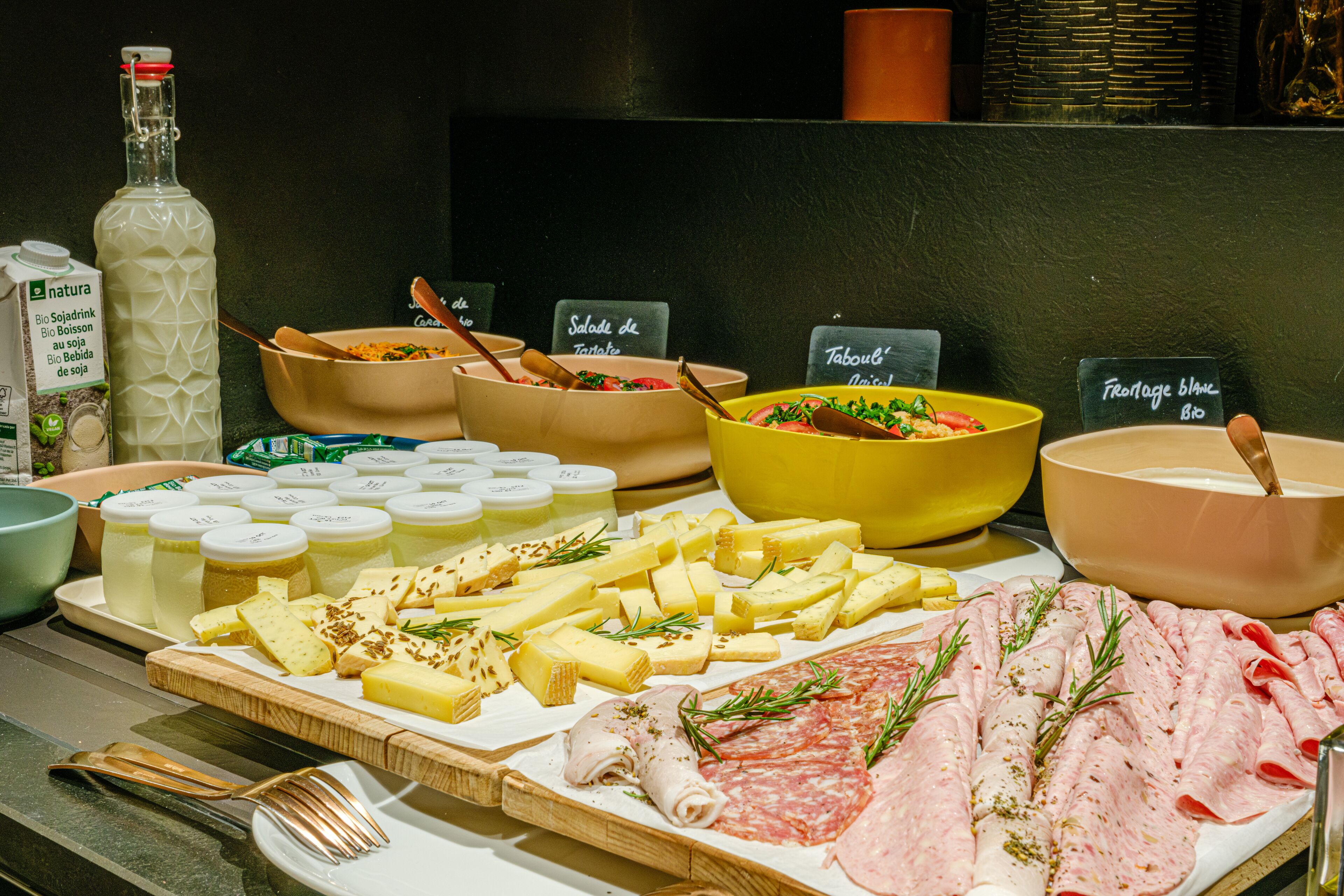 Een buffet met diverse kazen, vleeswaren en bijbehorende sauzen.
