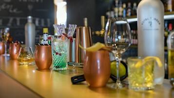 A bar with copper mugs, a cocktail shaker, and various bottles in the background.