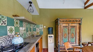 Una cucina con piano cottura a gas, dispenser d'acqua e un armadietto con ante decorate.
