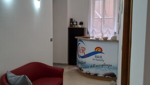 Amplia sala de estar con un sofá rojo, un área de cocina con desayunador y una ventana con cortinas.