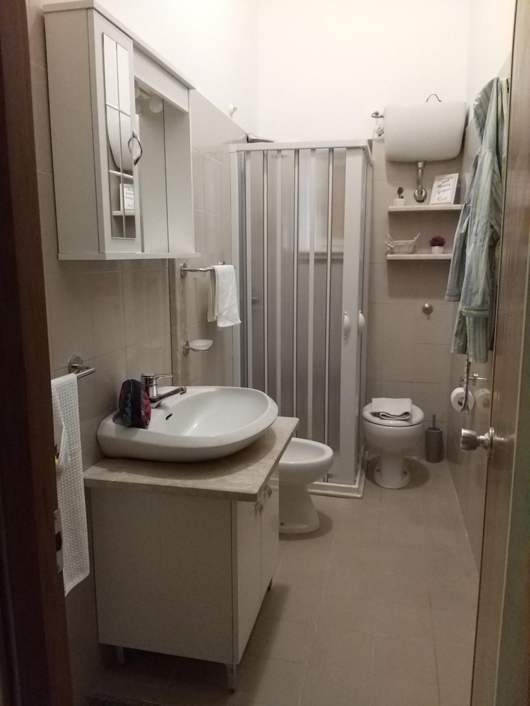 Ein kleines Badezimmer mit Waschbecken, Toilette und Duschkabine, alles in Weiß.
