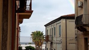 Una calle estrecha flanqueada por edificios, un cartel de stop visible y una palmera al fondo.