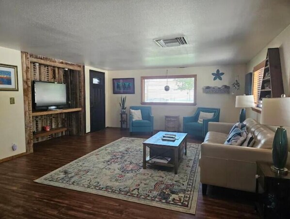 A living room with a television, sofa, coffee table, and a patterned rug. - Large country home with 3 bed rooms and 3 baths. (Lone Pine)