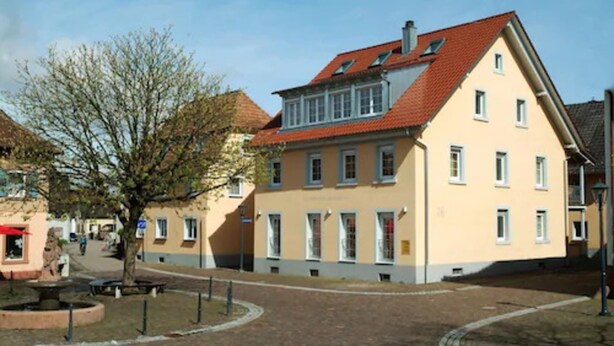 A two-story building with a red-tiled roof and a light yellow facade. - Ferienwohnungen am Sonnenplatz (Rust)
