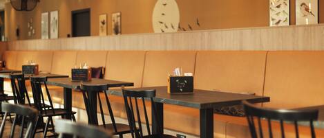 Un restaurante con una barra larga, sillas negras y lámparas colgantes.