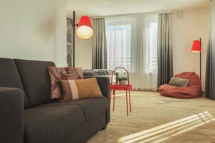 Una sala moderna con un sofá oscuro, sillas de acento rojas y una lámpara de pie roja.