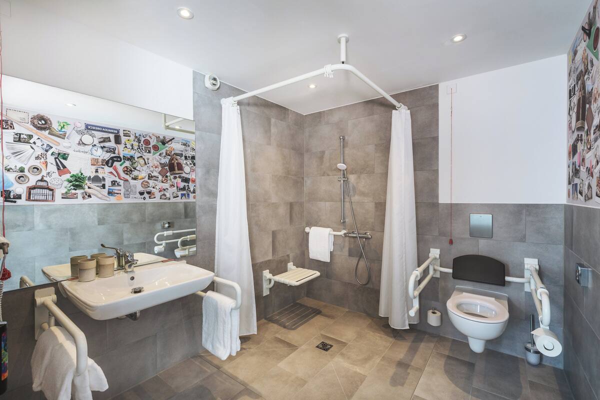 Une salle de bain moderne équipée d’une douche, de toilettes, d’un lavabo et d’un mur décoré de différents motifs.